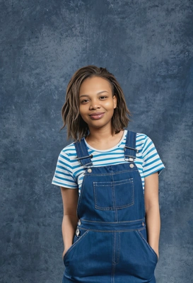 student with a layered haircut, in a denim overall dress, with a playful attitude, blue yearbook background, medium-shot 