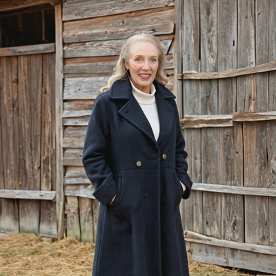 standing in front of a rustic barn, in wool coat