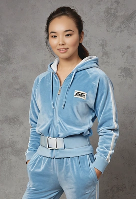 student in a solid baby blue velour tracksuit, accessorized with a chunky belt, against a classic yearbook background, medium shot photo 