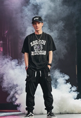 as a K-pop rapper, wearing a black snapback and a trendy oversized t-shirt with joggers, performing on stage with flashing lights and smoke machines