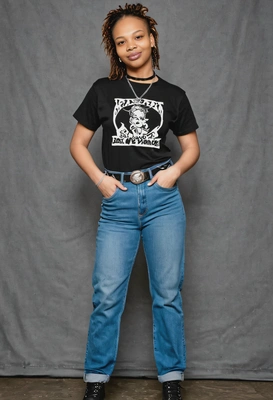 as a 90s riot grrrl, in a band tee tucked into high-waisted jeans, combat boots, and a choker necklace, with a confident stance against a classic yearbook backdrop, hands in pockets  