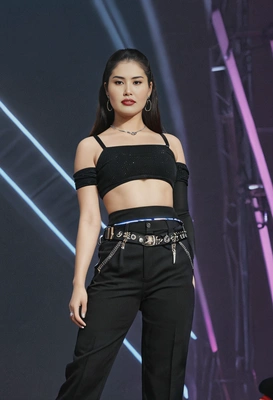 as Jennie from Blackpink, wearing a chic black crop top with high-waisted pants, standing on a stage with neon lights glowing in the background