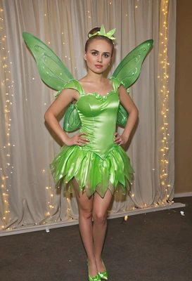dressed as Tinkerbell at a costume party, at a party room with twinkling lights, full-body image