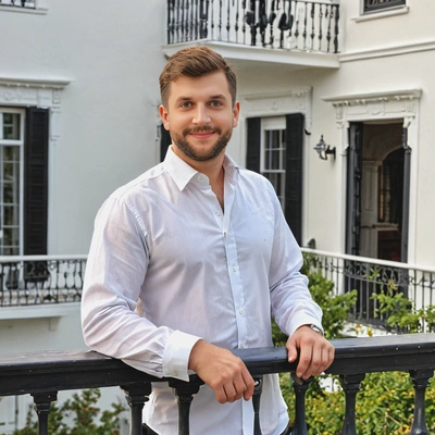 as a gentleman in white shirt, standing on the balcony of a historic house