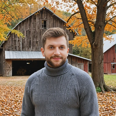 in front of an old barn in a turtleneck sweater, framed by autumn trees