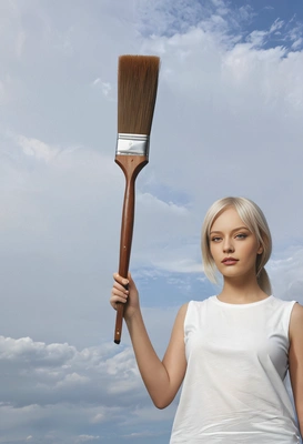 holding a giant paintbrush in front of a blank sky