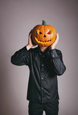 wearing a Halloween costume holding a pumpkin head in hands, blurred background, party lighting