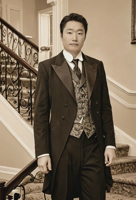 in 1920s tailcoat, standing by a grand staircase, with a soft sepia filter, blurred background